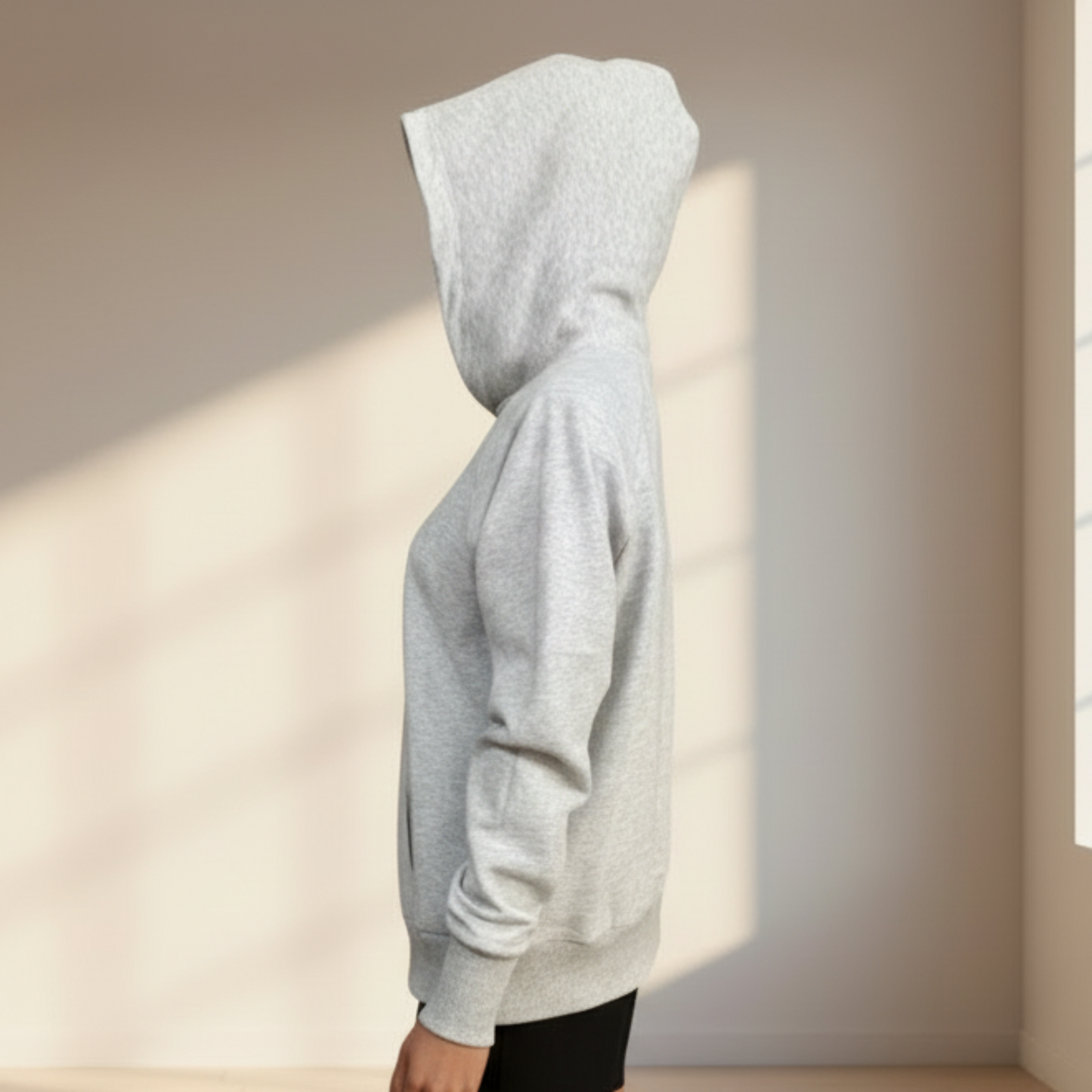 Mannequin wearing a gray hoodie in a room with a window and wooden floor.
