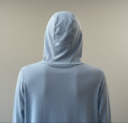 Person wearing a light blue hoodie with a blurred indoor background